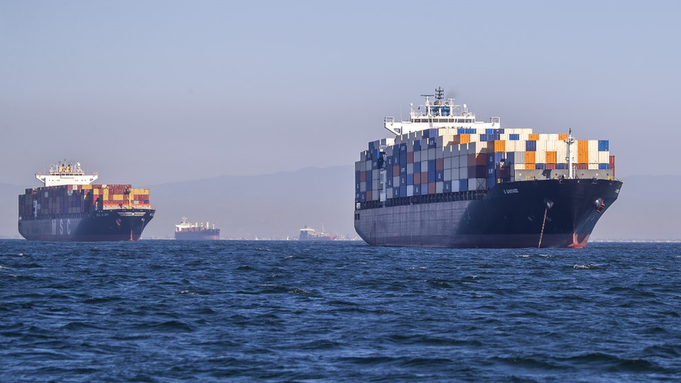 Two ships full of containers, and two more in the background, off the port of Los Angeles.