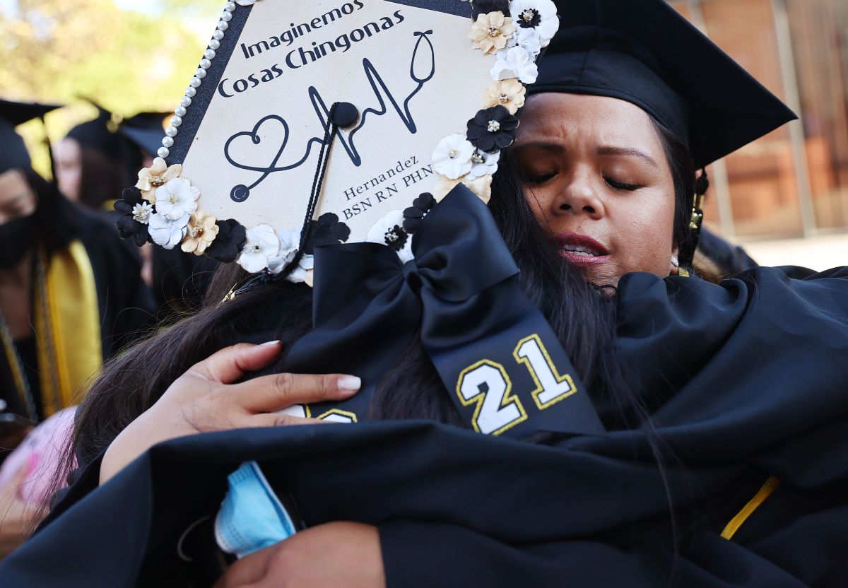 LOS ANGELES, CALIFORNIA - JULY 27: Cal State Los Angeles graduate Maricris Trask (R), who is a mother and U.S. Navy veteran, hugs another graduate after their graduation ceremony that is performed outdoors under a tent on campus on July 27, 2021 in Los Angeles, California.